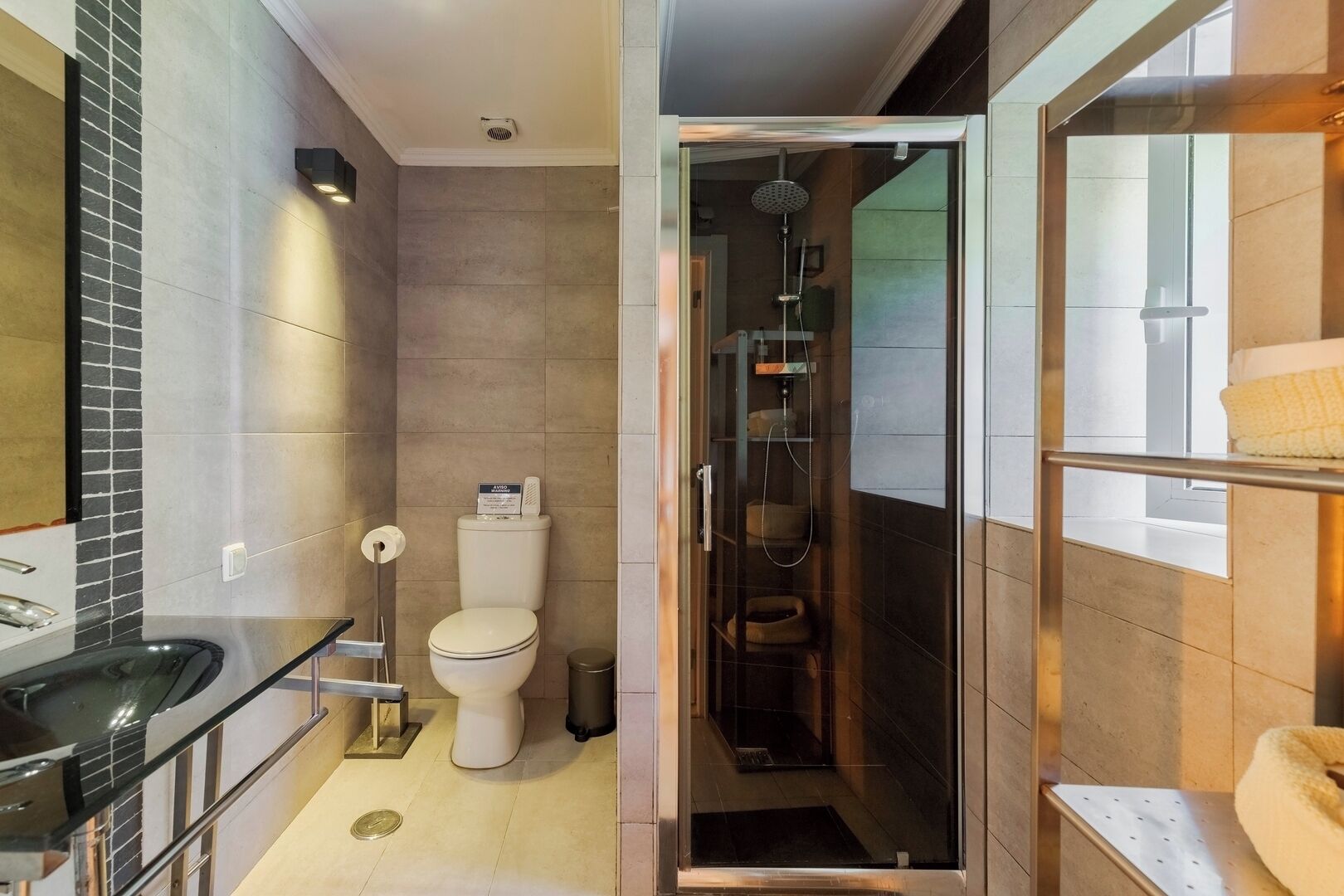 A modern bathroom with a glass-enclosed shower, a toilet, and a sink.