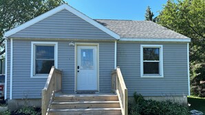 A single-story house with a front porch, a garage door, and a small front yard. - Charming Algoma retreat - 10 min. Walk to the Beach (Algoma)