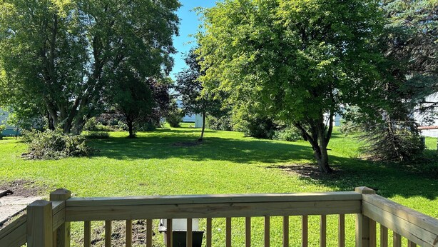 A wooden deck with a grassy yard and trees. - Charming Algoma retreat - 10 min. Walk to the Beach (Algoma)