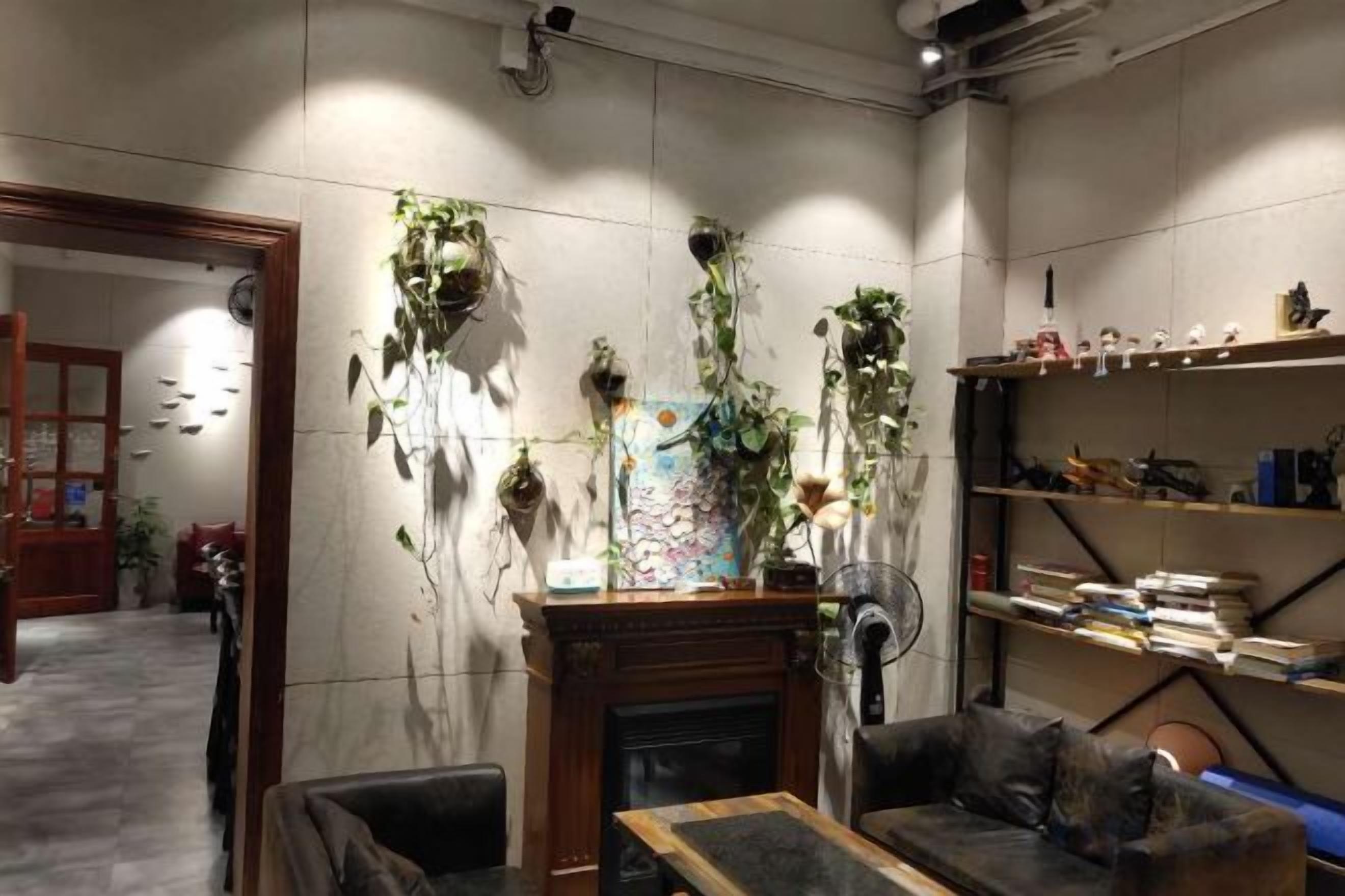 A room with a fireplace, a sofa, a coffee table, and shelves with books and decorative items.
