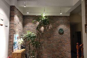 A room with a brick wall, a wooden cabinet, and a hanging plant.