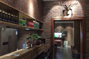 A bar area with a brick wall, shelves with beverages, a refrigerator, and a mounted deer head.