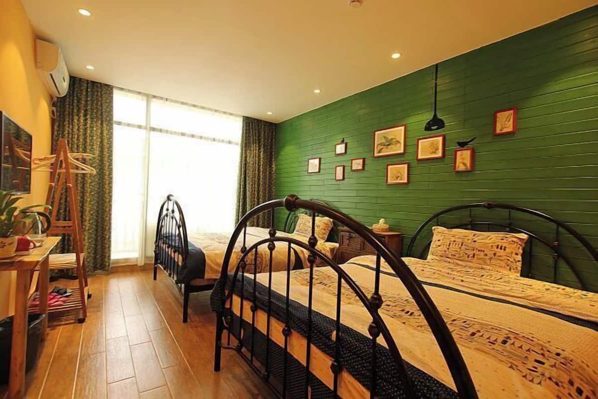 A bedroom with two beds, a desk, a chair, and a window with curtains.