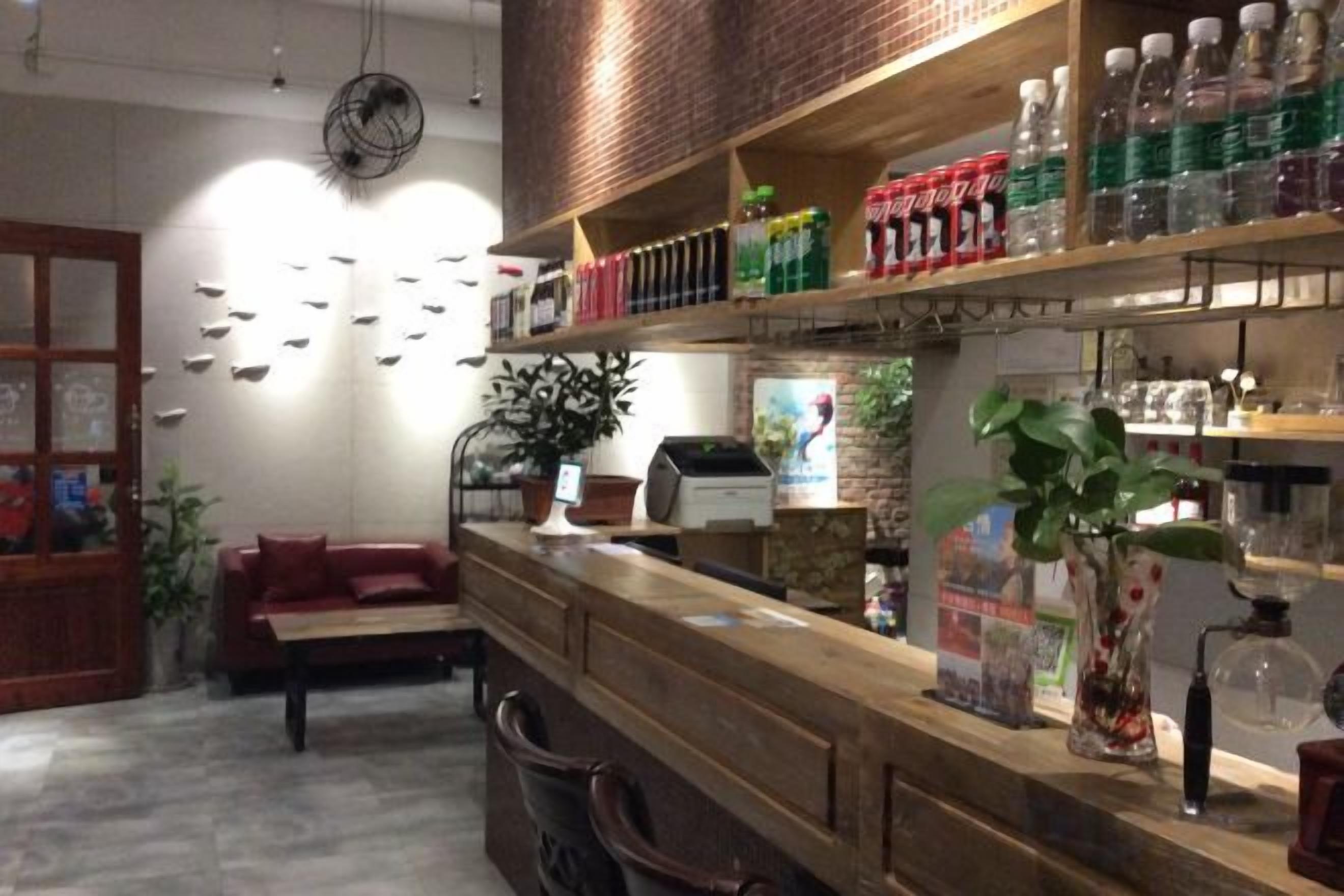 A bar area with shelves stocked with bottles, a seating area with a red couch, and a wall with decorative items.