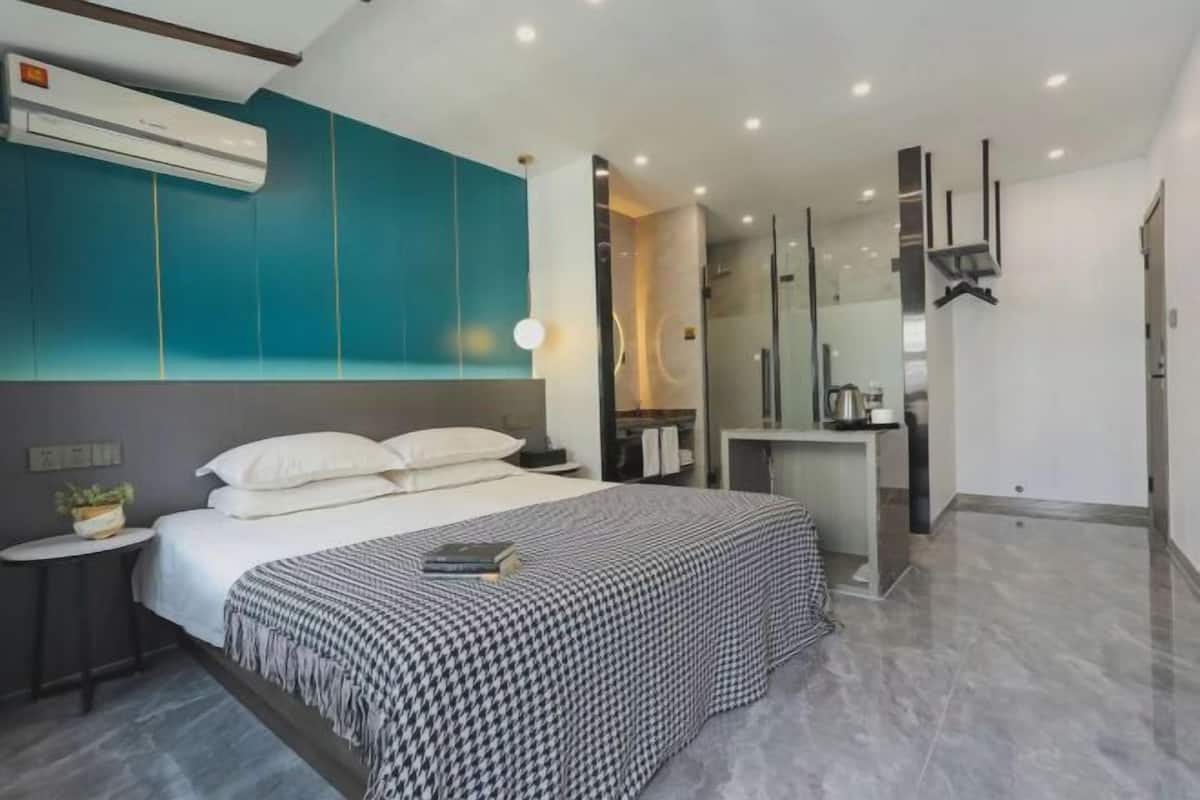 Ein modernes Schlafzimmer mit einem großen Bett, Nachttischen, einem Einbauschrank und einer Duschkabine.
