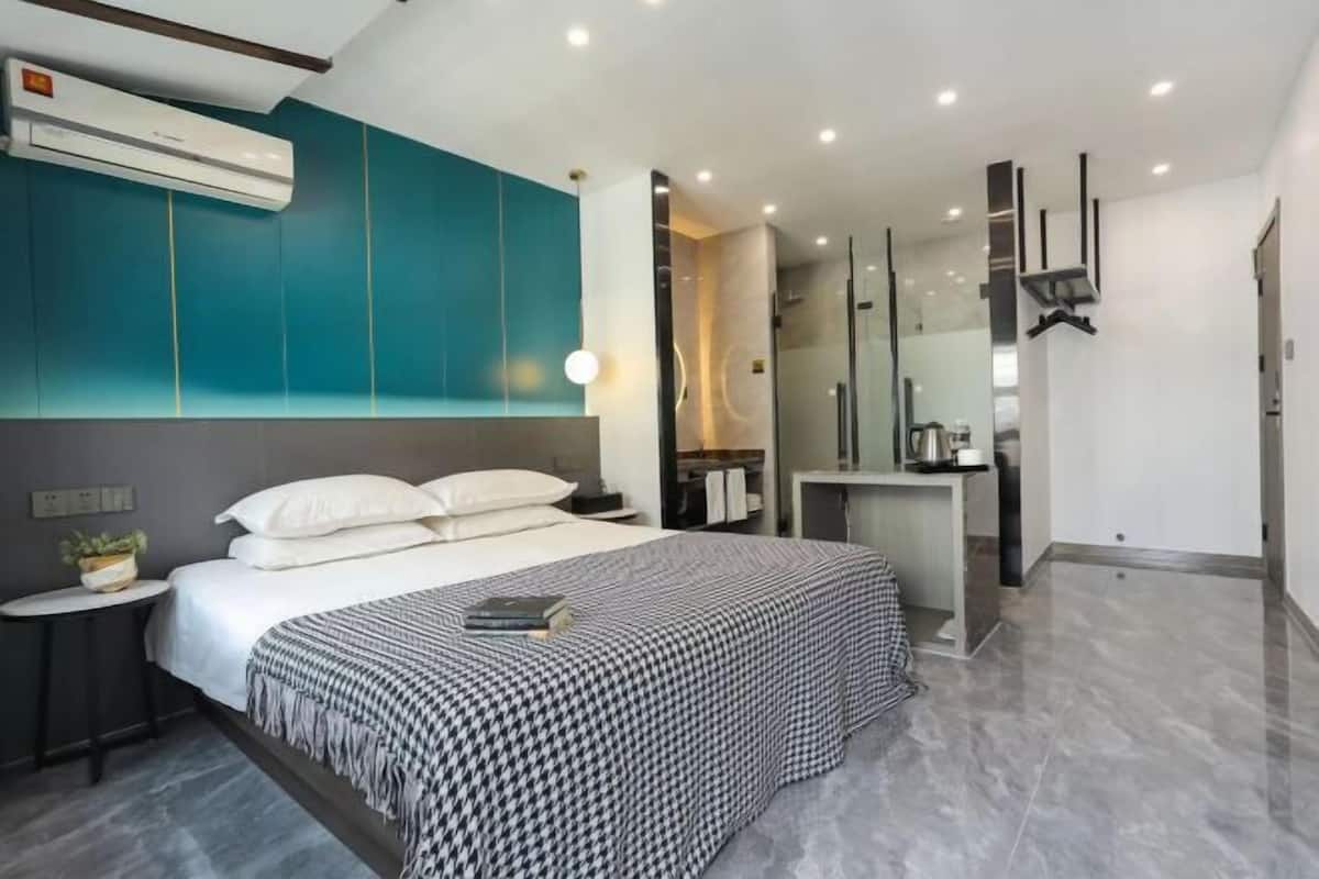 Ein modernes Schlafzimmer mit Bett, Nachttischen, einem Spiegel und einem Badezimmer mit Dusche und Waschbecken.