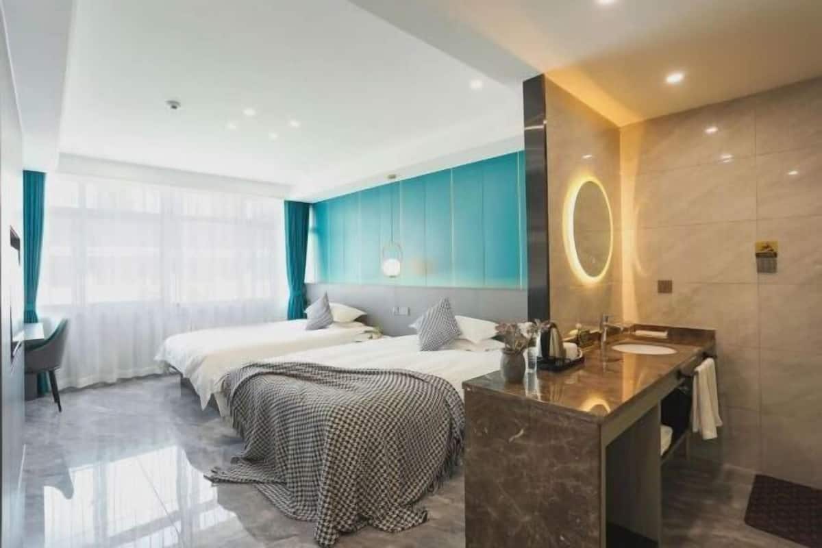 Ein modernes Hotelzimmer mit einem großen Bett, einer separaten Sitzecke, einem Badezimmer mit Waschtisch und einem großen Fenster, das für natürliches Licht sorgt.