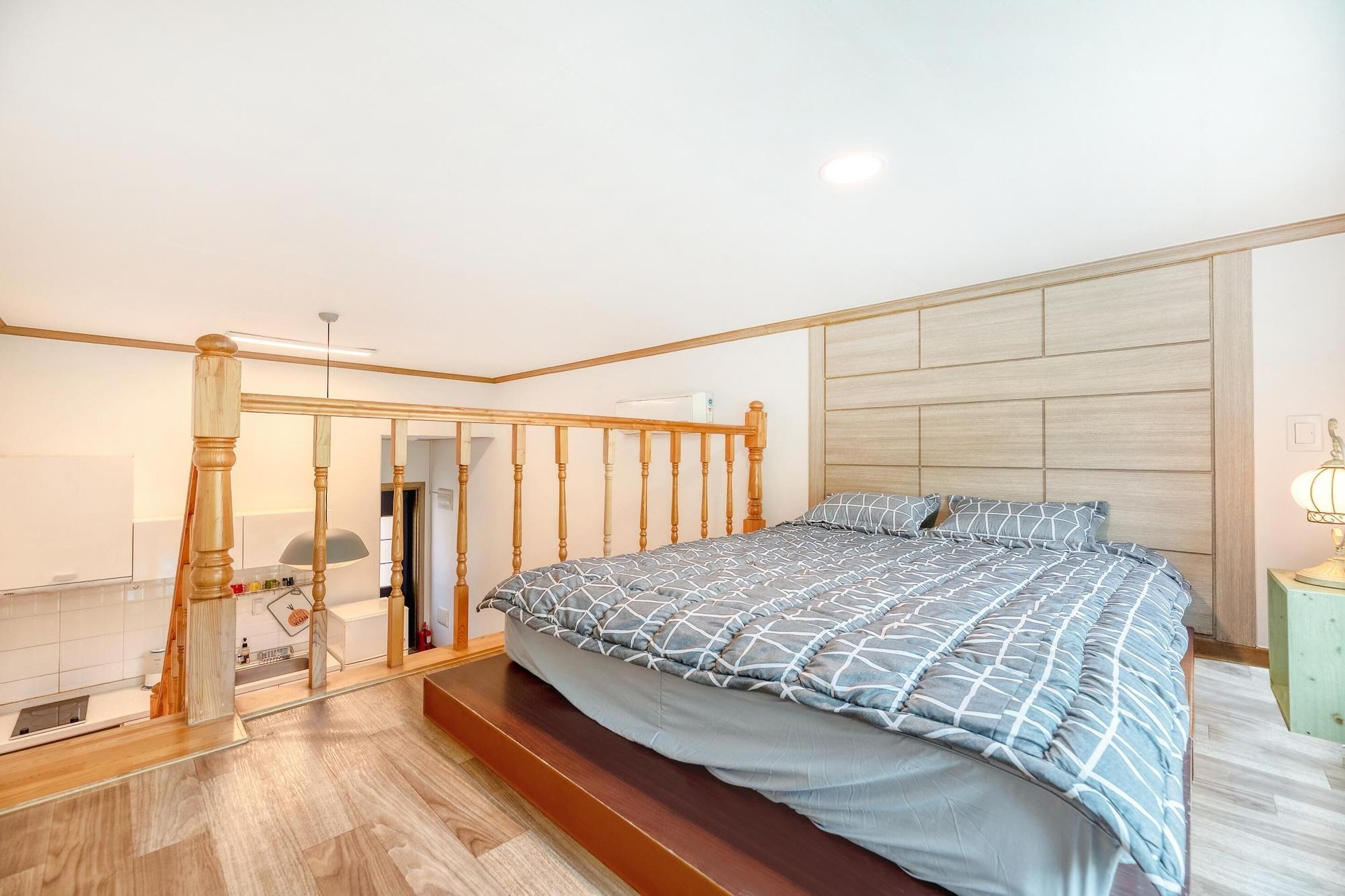 A bedroom with a bed, wooden headboard, and a staircase leading to an upper floor.