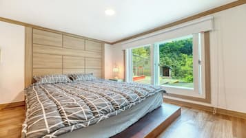 Un dormitorio moderno con una cama grande, cabecera de madera y puerta de cristal corredera que da a un balcón.