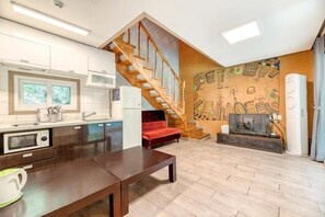 A modern kitchen with wooden cabinets, a red sofa, a wooden staircase, and a wall mural. - Gapyeong Swimteo Pet Pension (Gapyeong)