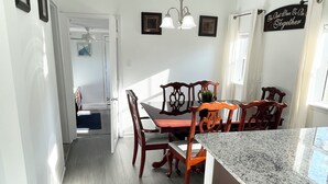 A modern kitchen with a granite countertop, wooden chairs, and a stainless steel trash can. - Spacious 4-bedroom house in enjoyable Pensacola with AC, WiFi (Pensacola)