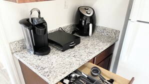 A kitchen with a granite countertop, a coffee maker, a Keurig, and a drawer organizer with utensils. - Spacious 4-bedroom house in enjoyable Pensacola with AC, WiFi (Pensacola)