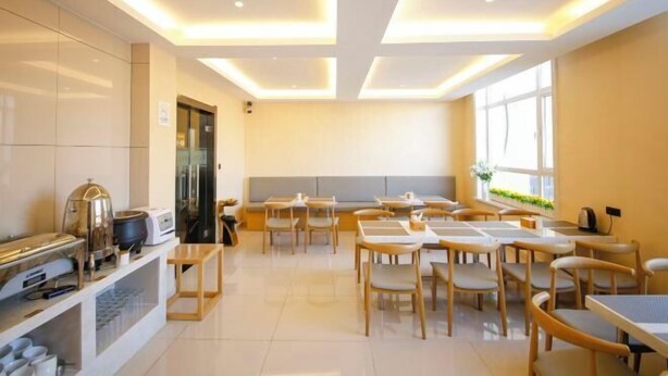 A modern dining area with tables and chairs, a buffet station, and a large window providing natural light. - Hanxing Hotel (Jiaohe Station) (Jiaohe)