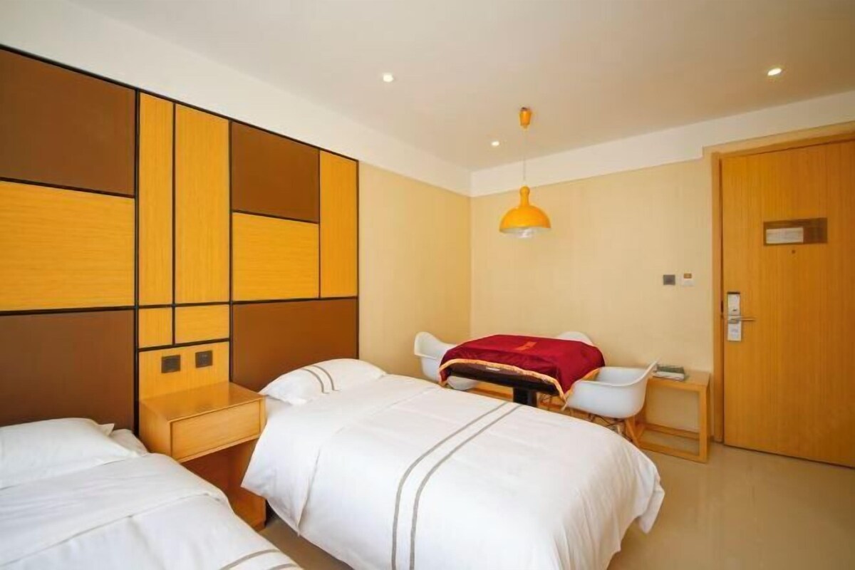 A hotel room with two beds, a desk, a chair, and a door.