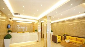 A modern hotel lobby with a reception desk, seating area, and decorative plants. - Hanxing Hotel (Jiaohe Station) (Jiaohe)