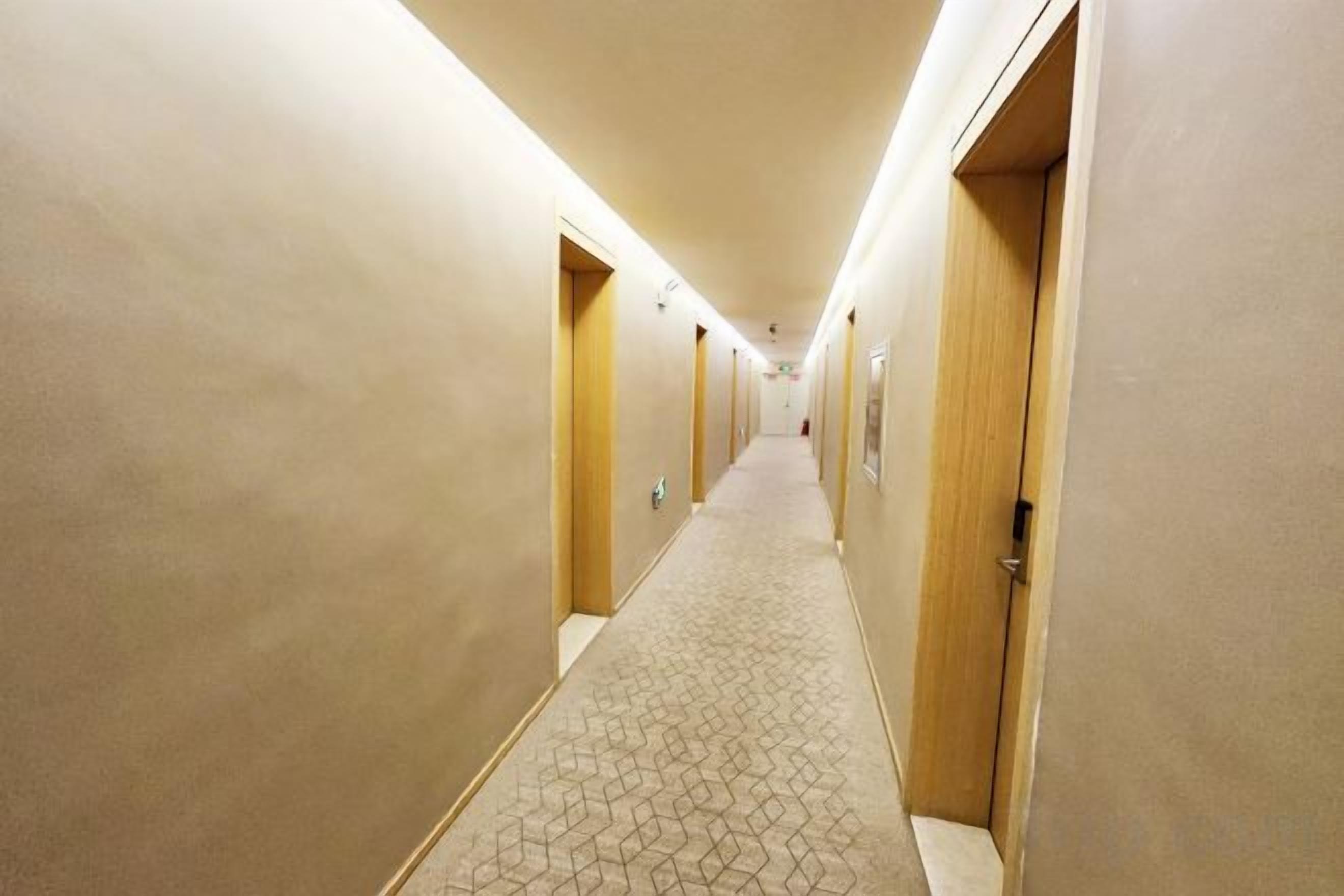 Un pasillo de hotel con pisos alfombrados y puertas de madera.