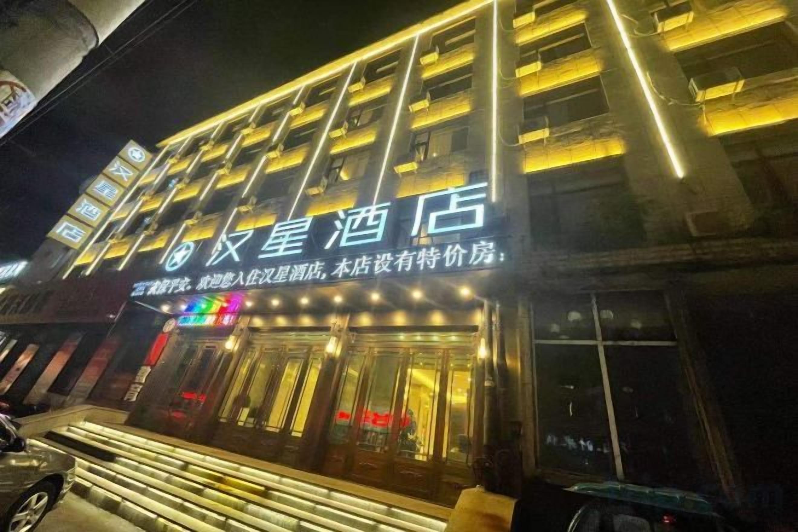 Un hotel con un letrero llamativo y ventanas iluminadas.