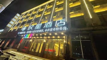 Un hotel con un letrero llamativo y ventanas iluminadas.