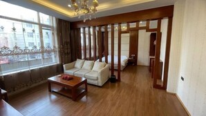 A spacious living room with a sofa, a coffee table, and a chandelier. - Hanxing Hotel (Jiaohe Station) (Jiaohe)