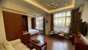 A hotel room with a bed, sofa, coffee table, TV, and a window with curtains. - Hanxing Hotel (Jiaohe Station) (Jiaohe)