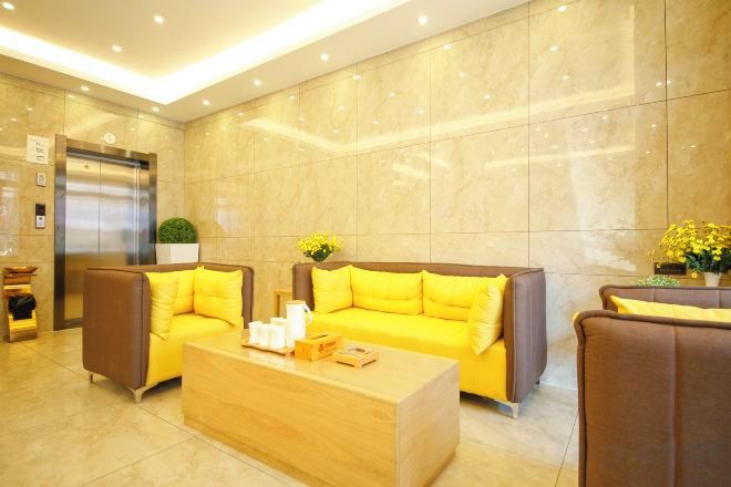 A lobby with a reception desk, two sofas, a coffee table, and a wall-mounted elevator.