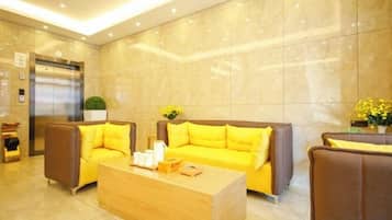 A lobby with a reception desk, two sofas, a coffee table, and a wall-mounted elevator.