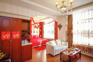 A room with a bed, a sofa, a wooden cabinet, and a chandelier.