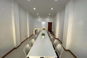 Un salón de conferencias con una larga mesa, sillas y una pizarra.