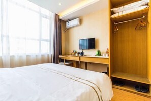A hotel room with a bed, a desk, a television, and a wardrobe.