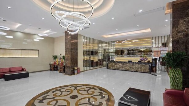 Een moderne hotel lobby met een receptiebalie, zithoek en decoratieve verlichting.