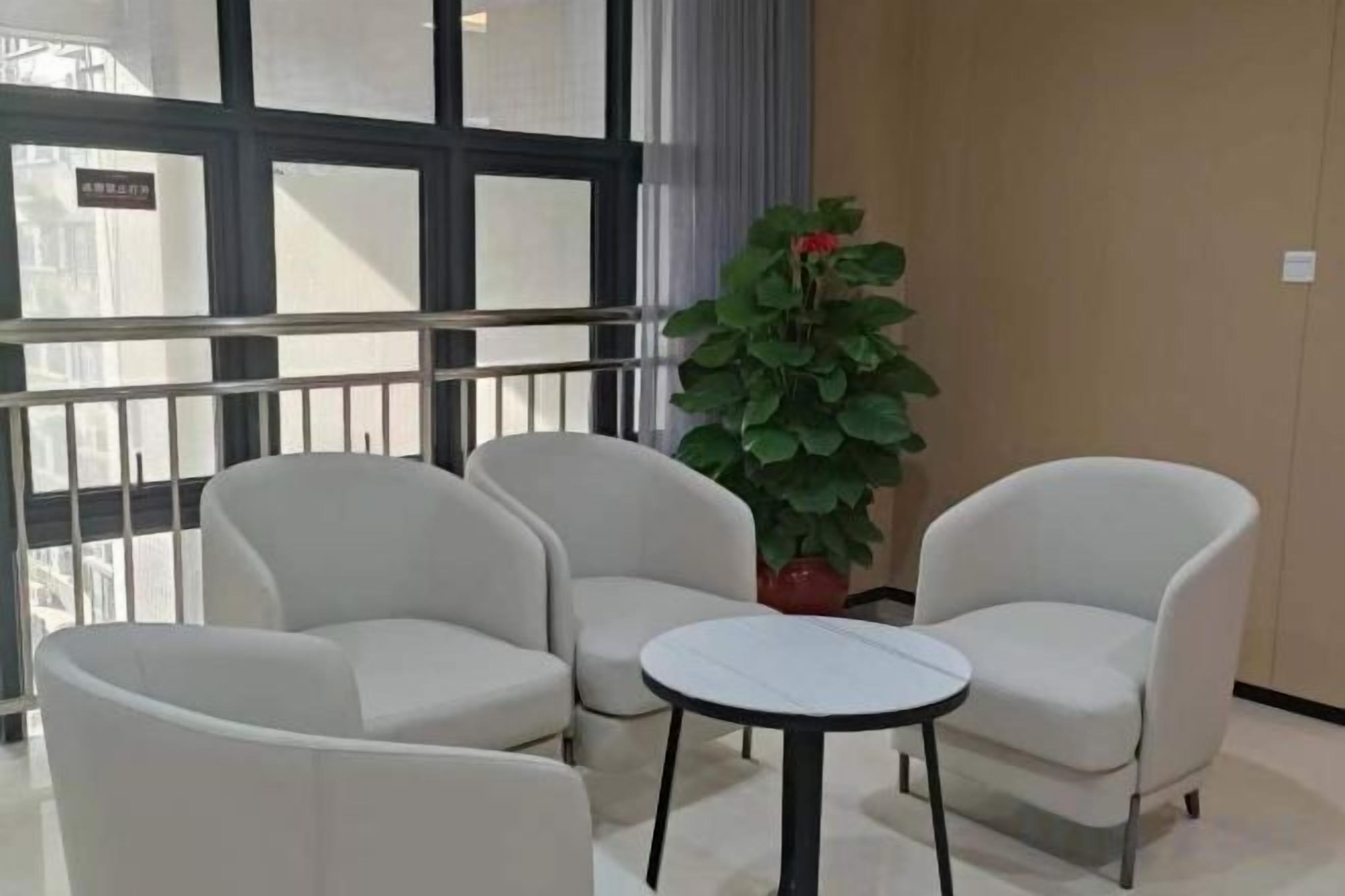 A room with a balcony, two armchairs, a small round table, and a potted plant.