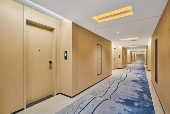 A hotel hallway with doors, a carpeted floor, and recessed lighting.