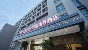 Een hotel met een moderne gevel, met een opvallend bord met Chinese karakters en een geometrisch ontwerp.