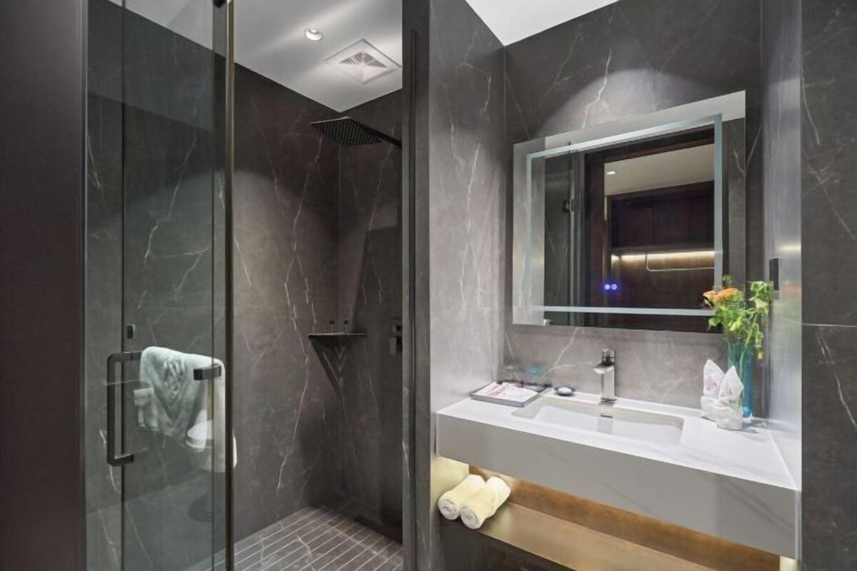 Une salle de bain moderne avec une douche à parois de verre, un meuble-lavabo avec un miroir et une étagère en bois.