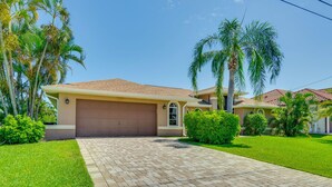A residential house with a garage, paved driveway, and well-maintained lawn. - Holly's HomeAway-Private Pool, Kayaks & Canal Adventures (Cape Coral)
