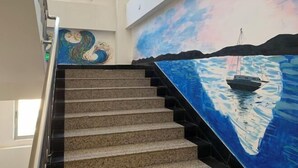 A staircase with a painting of a sailboat on the wall. - Yulai Hotel (Kunming)