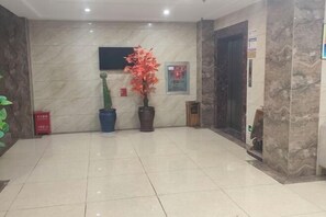A lobby with a marble floor, a reception desk, a potted plant, and a framed sign on the wall. - Yulai Hotel (Kunming)