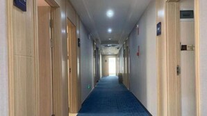 A hotel hallway with wooden doors, a blue carpet, and a ceiling with recessed lighting. - Yulai Hotel (Kunming)