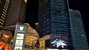 A modern hotel with a distinctive curved facade, illuminated signage, and a prominent entrance with a glass canopy. - Yulai Hotel (Kunming)