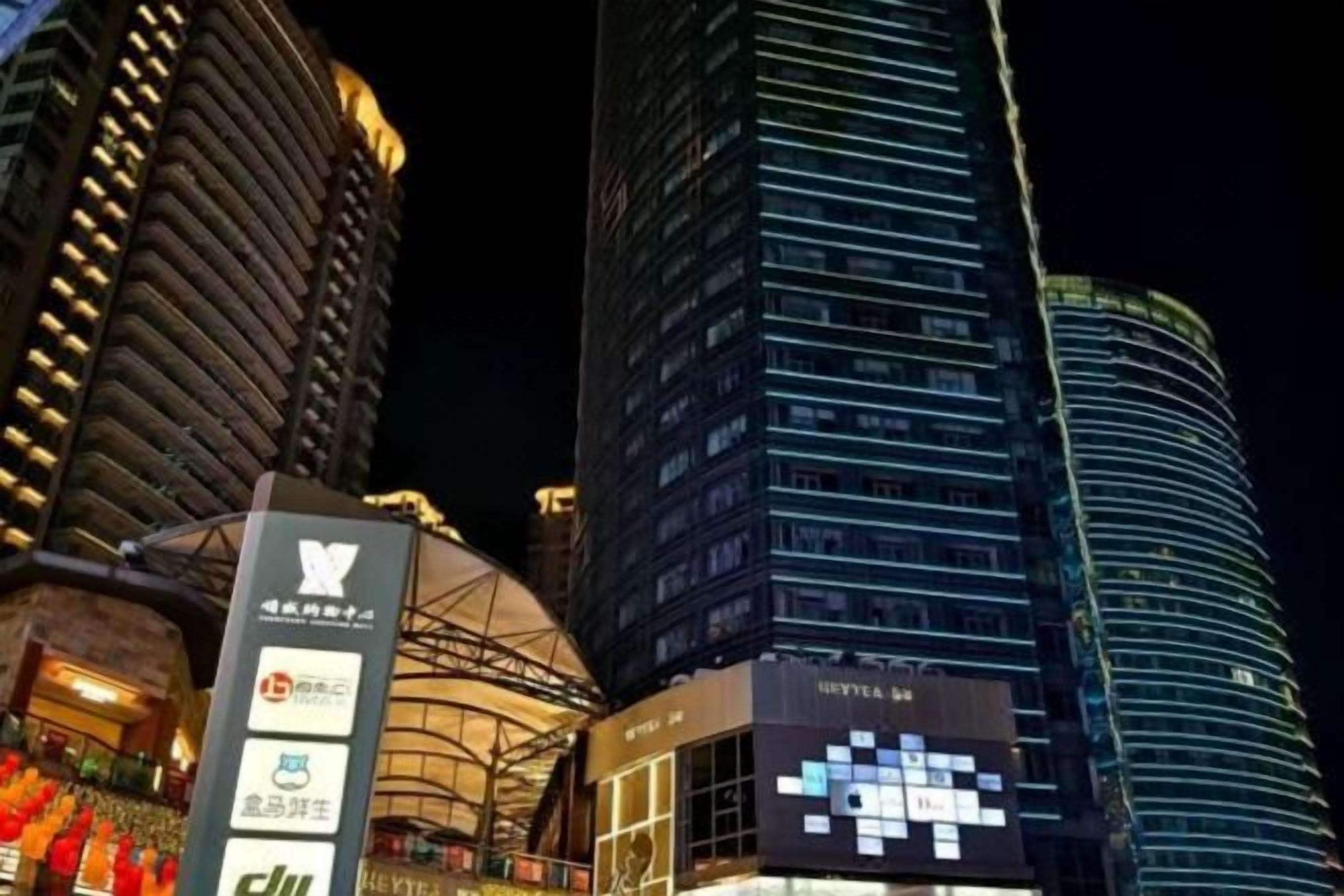 Un edificio de gran altura con señalización iluminada, un letrero destacado que dice 'HOTEL' y una pantalla digital.