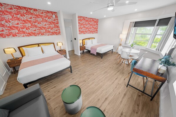 Ein Hotelzimmer mit zwei Betten, einem Schreibtisch, einem Stuhl und einem kleinen Tisch.