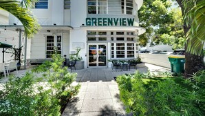 A building named 'Greenview' with a paved entrance, outdoor seating area, and surrounding greenery. - Standard Queen Room: Free Beach Chairs, Parking, &  more Included (Miami Beach)