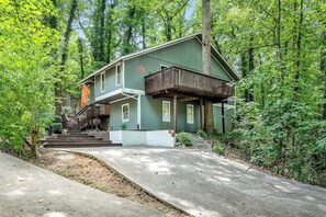 A two-story house with a porch, surrounded by trees.