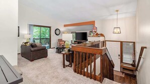 Ein Wohnzimmer mit einer Couch, einem Fernseher und einer Treppe.
