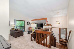 A living room with a sofa, TV, and a staircase.