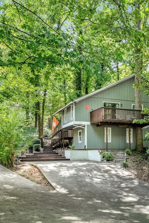 A building with a staircase leading to a balcony, surrounded by trees.