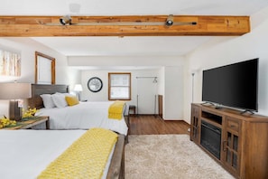 A bedroom with two beds, a TV, and a wooden ceiling.