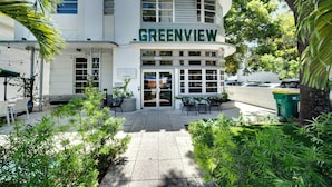 Ein Gebäude namens 'Greenview' mit befestigtem Eingangsbereich, Außenbereich mit Sitzgelegenheiten und umgebender Bepflanzung.