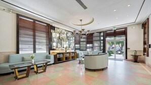 Eine Lobby mit einer Couch, einem Glastisch, einem Bücherregal und einer Rezeption.