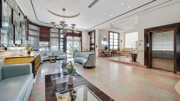 Eine großzügige Lobby mit modernem Design, ausgestattet mit einer Sitzecke, Sofas, einem Couchtisch, großen Fenstern für natürliches Licht und einer zentralen Kristallleuchtre.'